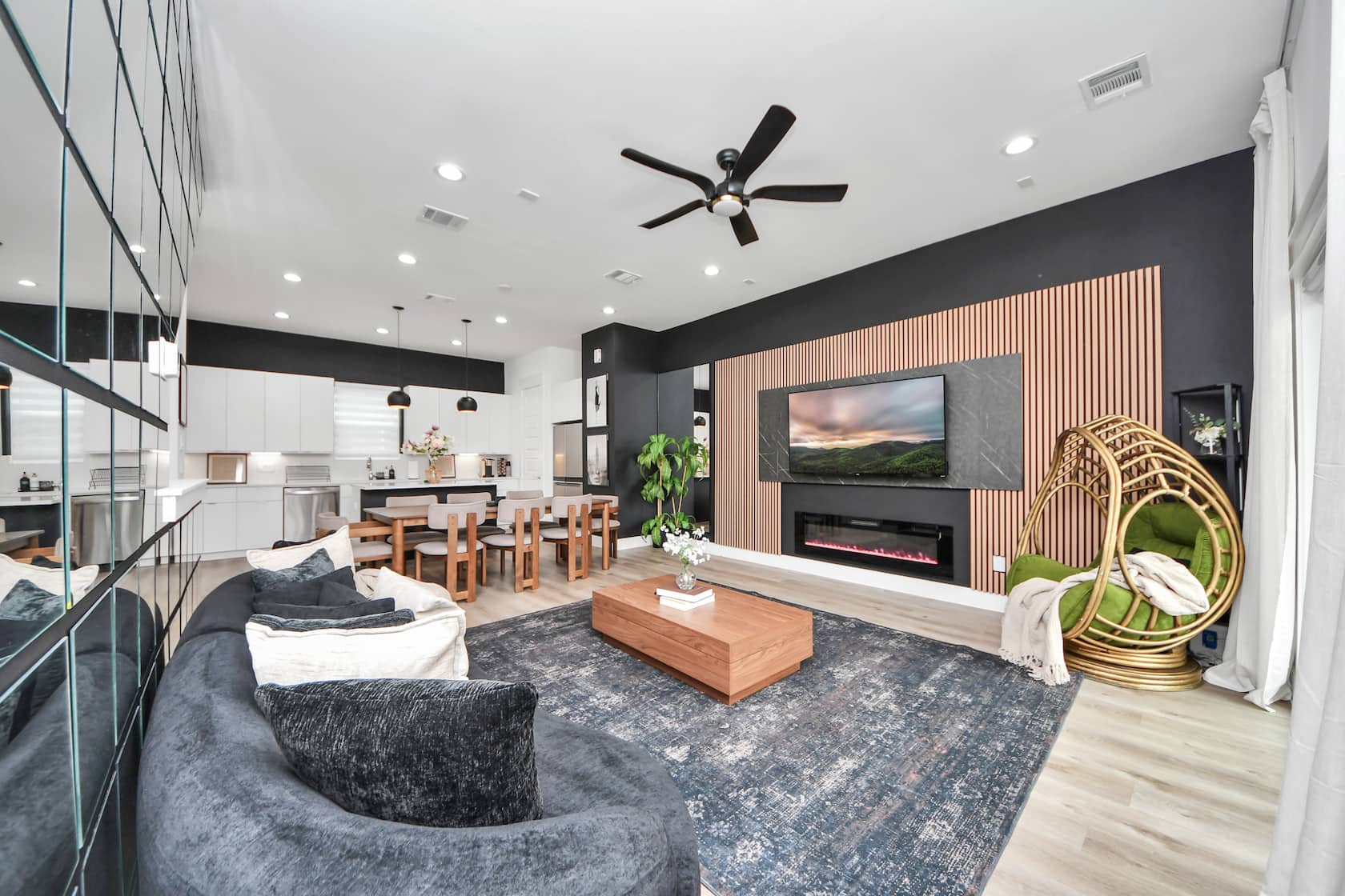 Open-plan living room with a sectional sofa, wood-slat feature wall and staircase