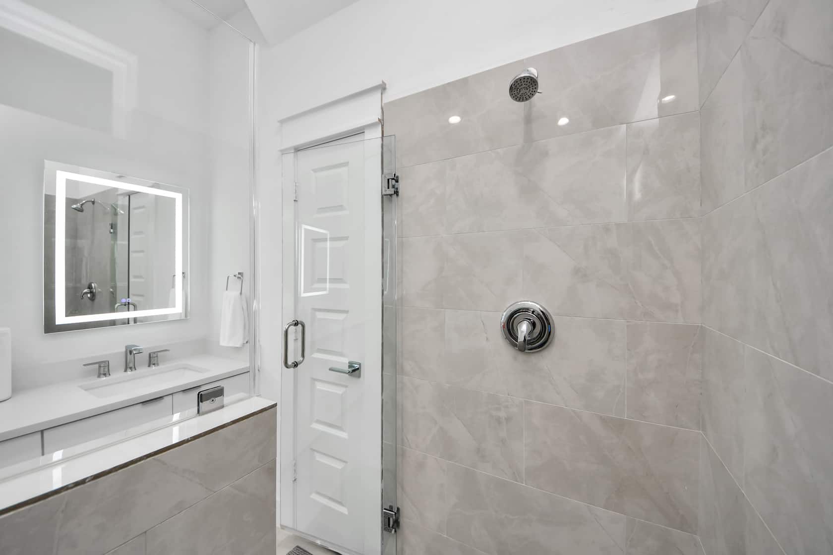 Walk-in shower with stone-look tiling and a backlit mirror