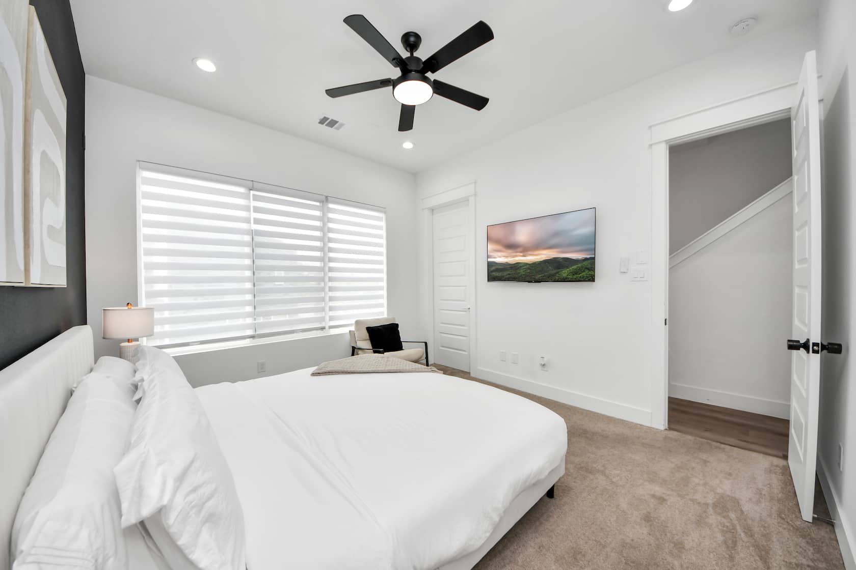 Primary bedroom with a large bed, wall-mounted television and wide window